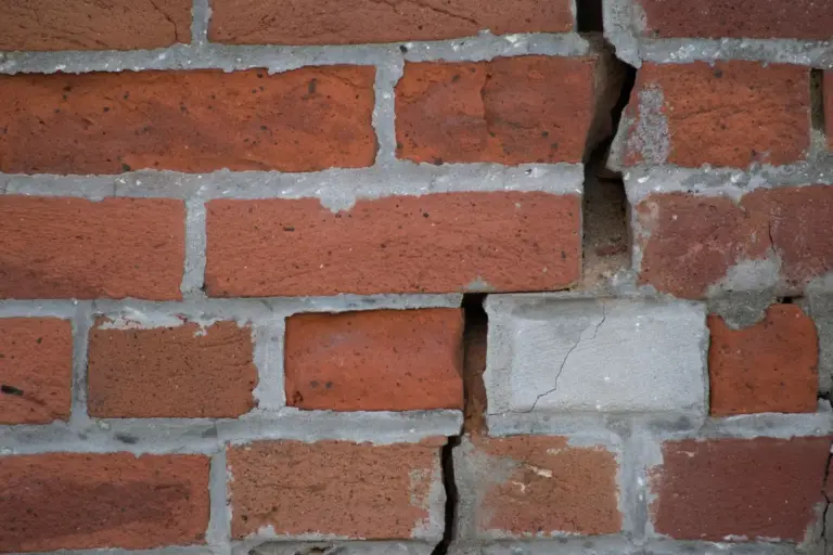 A long stair-step crack running down through a red brick wall