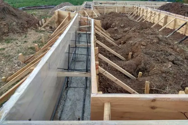 Wooden forms and steel rebar set in a trench, ready for a new concrete foundation footing