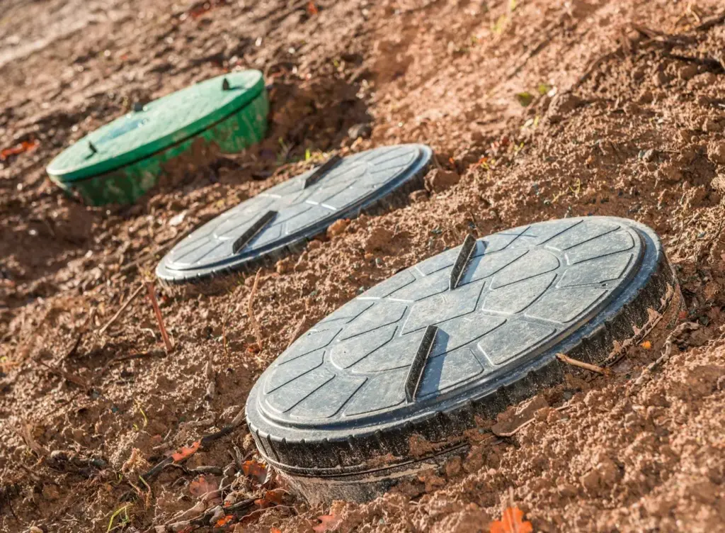 Round drain and catch-basin covers set into the soil of a yard